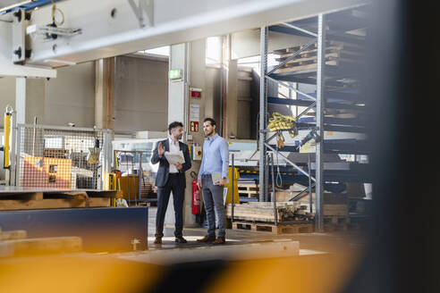 Junge und reife Geschäftsleute diskutieren in einer Fabrik - DIGF13022