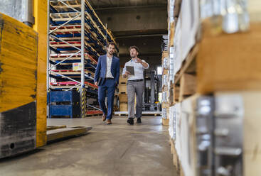 Man using digital tablet while inspecting warehouse with businessman at factory - DIGF13050