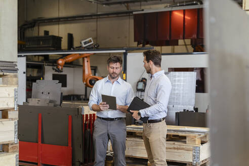 Geschäftsleute im Gespräch mit einem digitalen Tablet in einer Fabrik - DIGF13071