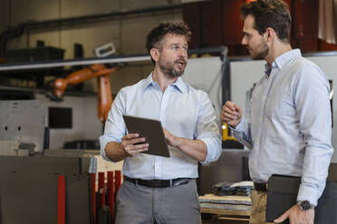 Geschäftsleute im Gespräch mit einem digitalen Tablet in einer Fabrik - DIGF13072