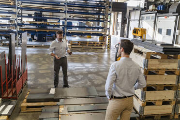 Business people standing by equipment while having discussion at factory - DIGF13077