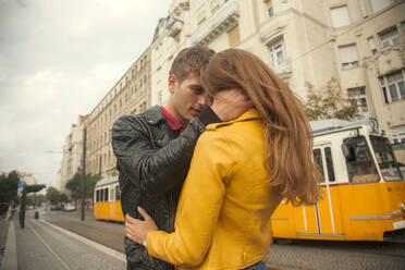 Young man embracing young woman in city - AJOF00507