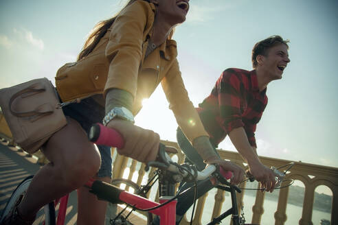 Glückliches Paar fährt Fahrrad gegen den Himmel an einem sonnigen Tag - AJOF00517