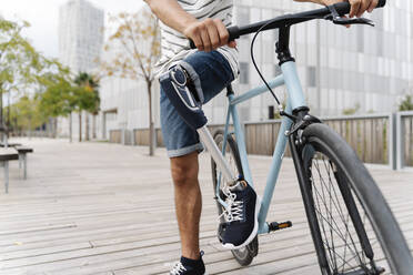 Tiefschnitt eines Mannes mit Beinprothese beim Fahrradfahren in der Stadt - JCZF00331