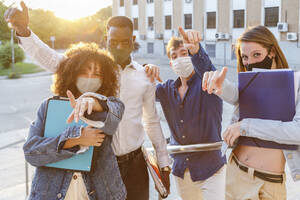 University students wearing protective face mask while pointing against education building - IFRF00053