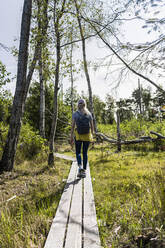 Female hiker walking along moorland boardwalk - CHPF00695