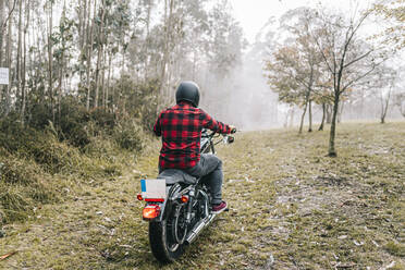 Mann beim Motorradfahren im Wald bei nebligem Wetter - DGOF01584