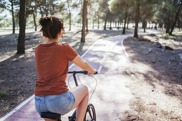 Woman riding bicycle at countryside during sunny day - MGRF00036