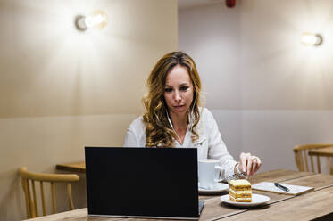 Unternehmerin mit Laptop bei einem Kaffee am Tisch - JMPF00518