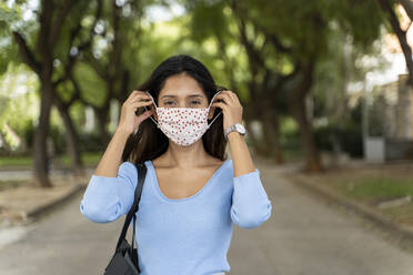 Beautiful female wearing protective face mask during COVID-19 - AFVF07529