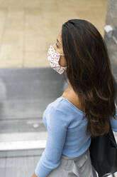 Contemplating woman looking away while standing on escalator during COVID-19 - AFVF07548