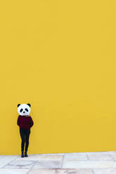 Frau mit Panda-Maske, die an einer gelben Wand steht - XLGF00772
