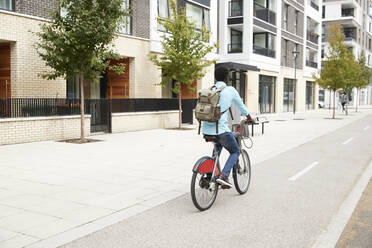 Mature man with backpack commuting on bicycle in city - PMF01501