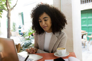 Unternehmerin, die im Café sitzend am Laptop arbeitet - VABF03881