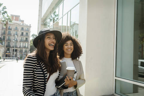 Glückliche weibliche Mitarbeiter stehen auf der Straße in der Stadt an einem sonnigen Tag - VABF03902