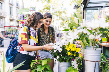 Lesbisches Paar kauft Blumen, während es auf der Straße in der Stadt steht - DGOF01608