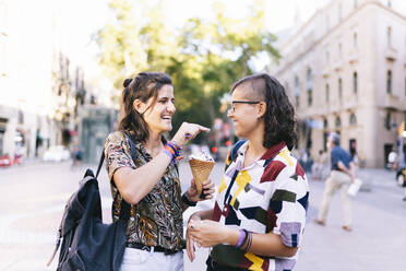 Lesbian daubing ice cream on girlfriend's nose while standing in city - DGOF01614