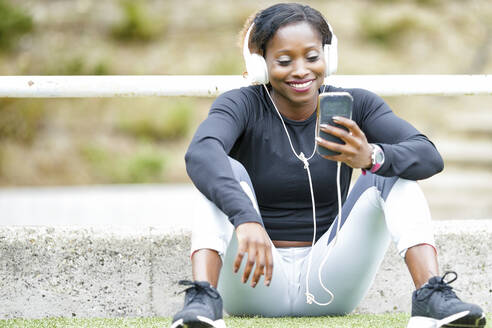 Lächelnde Sportlerin, die mit ihrem Smartphone Musik hört - GGGF00048