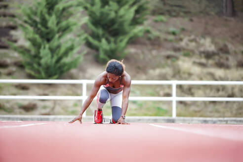 Female runner getting ready at start block - GGGF00055