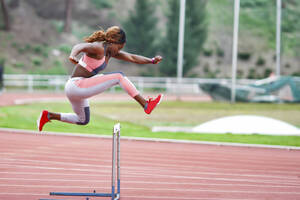 Junge Sportlerin springt beim Training über eine Hürde - GGGF00057