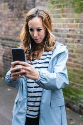 Mittlere erwachsene Frau, die mit dem Handy fotografiert, während sie in der Stadt steht - JMPF00526