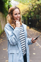 Smiling woman talking on mobile phone while exploring city - JMPF00529