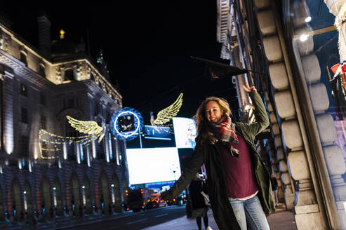 Unbekümmerte Frau tanzt auf der Regent Street während der Weihnachtszeit in London, UK - JMPF00545