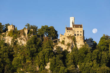 Deutschland, Baden-Württemberg, Schloss Lichtenstein in der Abenddämmerung mit Mondaufgang im Hintergrund - WDF06387