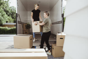 Women unloading boxes from moving van - MASF20373