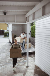 Portrait of smiling female and male partners unloading cardboard boxes during relocation - MASF20446