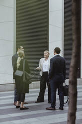 Lächelnde Unternehmerin im Gespräch mit Kollegen, während sie in der Stadt steht - MASF20472
