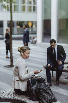 Unternehmer nutzt Smartphone, während er in der Stadt sitzt - MASF20491