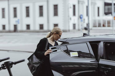 Businesswoman with bag sitting in car - MASF20515