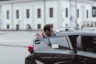 Businessman with smart phone sitting in car - MASF20528