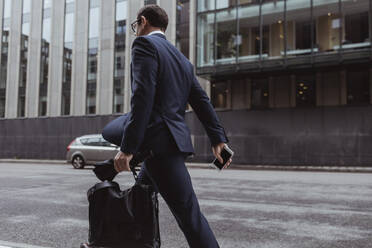 Side view of businessman with bag walking in city - MASF20539