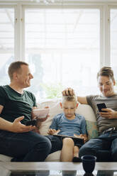 Lächelnde Väter sprechen, während der Sohn zu Hause ein digitales Tablet benutzt - MASF20591