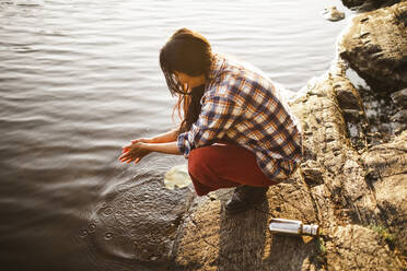 Hochwinkelaufnahme einer Frau, die sich am See im Wald die Hände wäscht - MASF20630