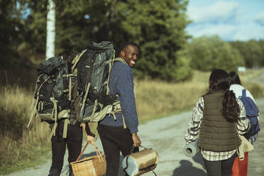 Portrait of smiling male with friends walking on footpath - MASF20668