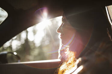 Lächelnde Frau schaut während der Fahrt im Auto weg - MASF20689