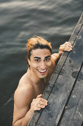 Portrait of smiling young man in lake during sunset - MASF20694