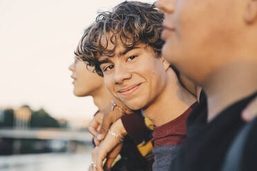 Porträt eines lächelnden Teenagers mit Freunden in der Stadt stehend - MASF20706