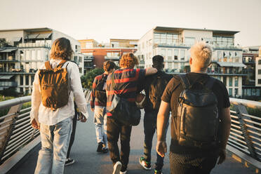 Young and teenage male friends walking on bridge in city - MASF20718