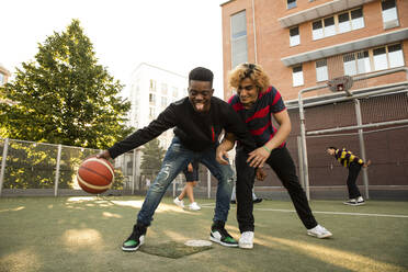 Männliche Freunde mit Basketballspielen auf dem Sportplatz - MASF20752