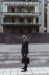 Full length portrait of male entrepreneur with bag standing in city - MASF20827