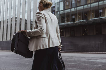 Rückansicht eines Unternehmers mit Tasche beim Spaziergang in der Stadt - MASF20846