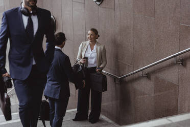 Geschäftsleute unterhalten sich auf Stufen, während ein Mitarbeiter in der Stadt Stufen erklimmt - MASF20851