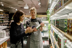 Verkäuferin assistiert weiblichen Kunden im Supermarkt - MASF20865