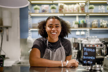 Portrait of smiling saleswoman at checkout counter in grocery store - MASF20878