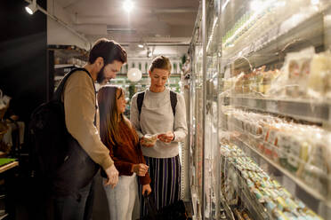 Woman reading ingredient while standing by family in supermarket - MASF20883