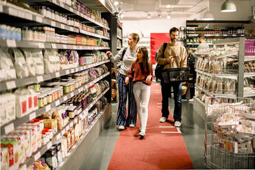 Familie mit Tochter geht beim Einkaufen im Supermarkt im Flur - MASF20898